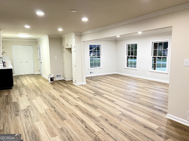 unfurnished living room with light wood-type flooring, plenty of natural light, and crown molding