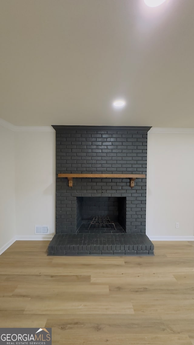 details with a brick fireplace, wood-type flooring, and ornamental molding