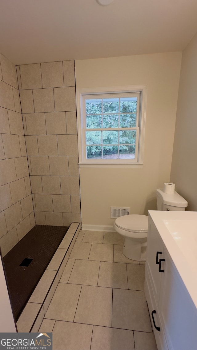 bathroom featuring tiled shower, toilet, vanity, and tile patterned floors