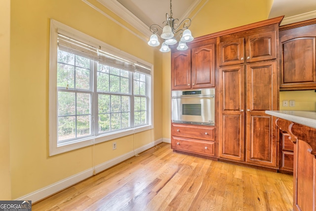 kitchen featuring crown molding, light wood-type flooring, a notable chandelier, pendant lighting, and oven