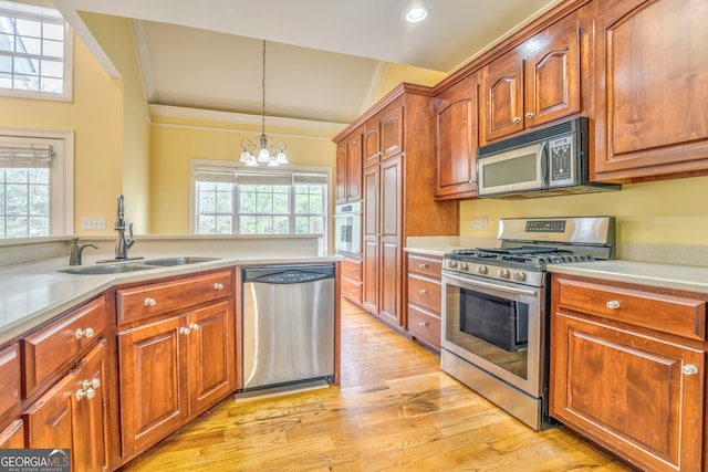 kitchen featuring stainless steel appliances, decorative light fixtures, a notable chandelier, sink, and light hardwood / wood-style flooring