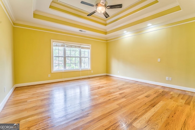 spare room with ornamental molding, light wood-type flooring, and a tray ceiling