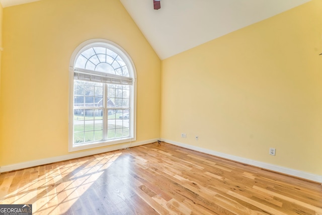 spare room with light wood-type flooring and high vaulted ceiling