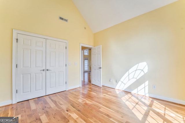 unfurnished bedroom with a closet, light hardwood / wood-style flooring, and high vaulted ceiling