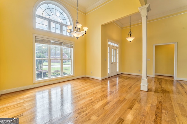 entrance foyer featuring a high ceiling, a healthy amount of sunlight, light wood-type flooring, and decorative columns