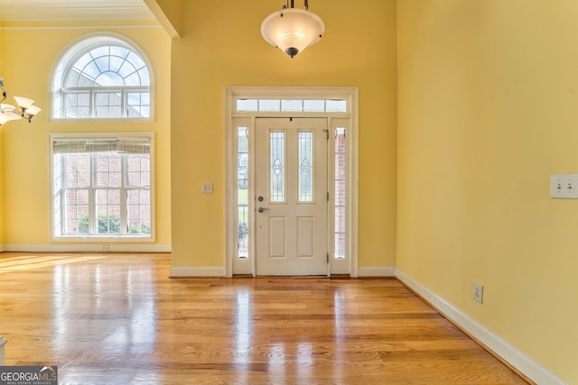 entryway with light hardwood / wood-style floors and crown molding