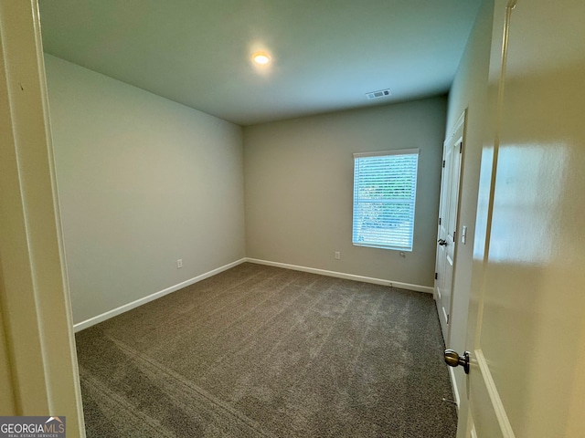 unfurnished room featuring dark carpet