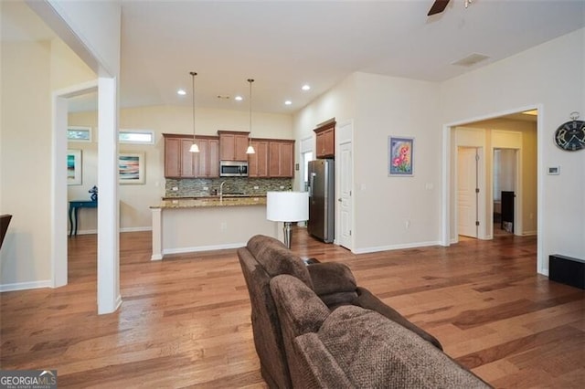 living room with light wood-type flooring, sink, vaulted ceiling, and ceiling fan