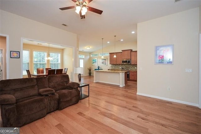 living room with light hardwood / wood-style floors, ceiling fan, and vaulted ceiling