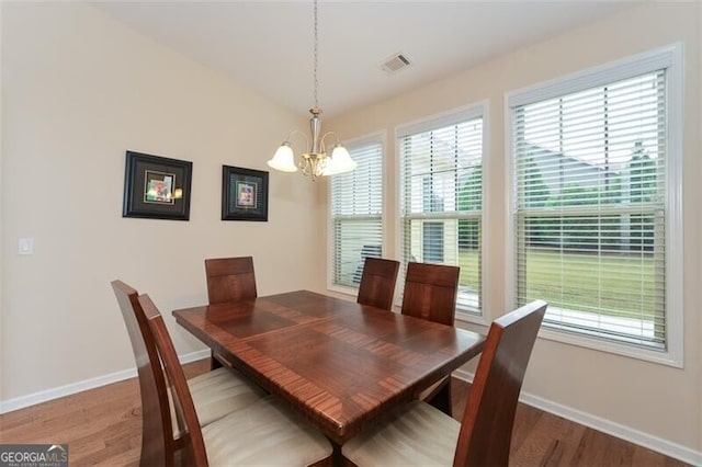 dining space with hardwood / wood-style floors and an inviting chandelier