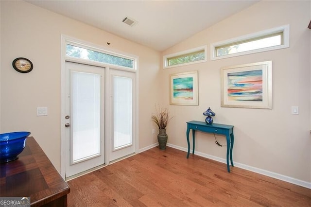 doorway to outside featuring light hardwood / wood-style flooring, lofted ceiling, and plenty of natural light