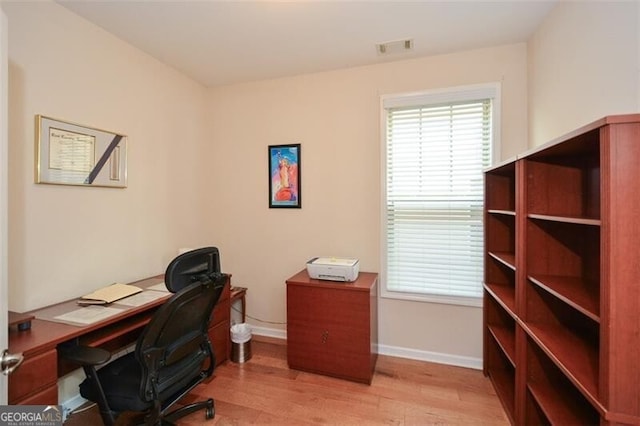 home office with light hardwood / wood-style flooring