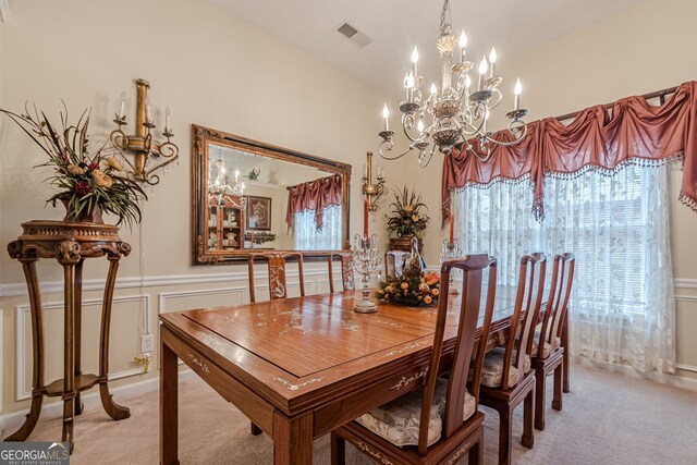 carpeted dining space featuring a notable chandelier