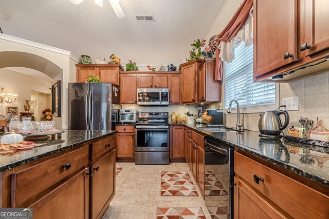 kitchen featuring appliances with stainless steel finishes, sink, backsplash, and dark stone countertops