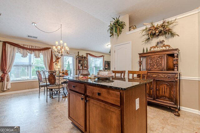 kitchen featuring dark stone counters, a kitchen island, decorative light fixtures, vaulted ceiling, and a chandelier