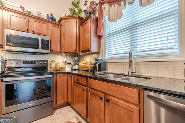 kitchen with dark stone counters, decorative backsplash, sink, and stainless steel appliances