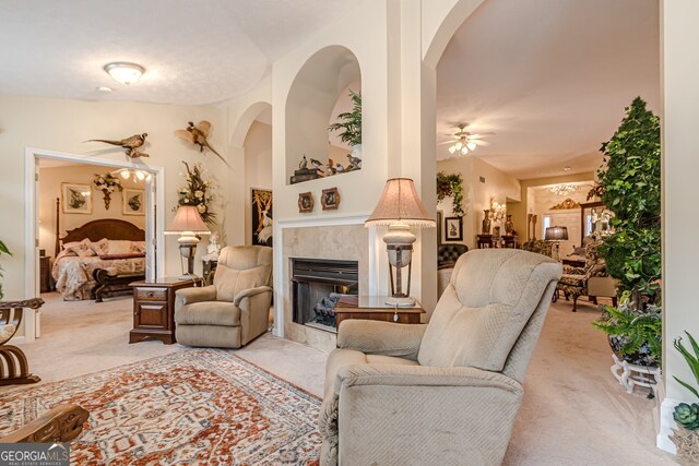 living room with a fireplace, light carpet, and ceiling fan