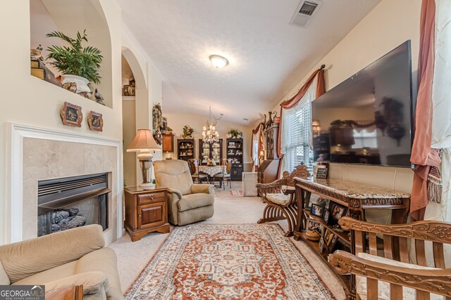 carpeted living room featuring an inviting chandelier, vaulted ceiling, a tile fireplace, and a textured ceiling