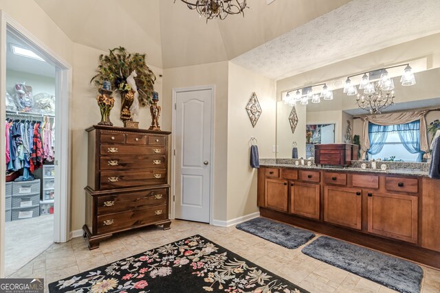 bathroom featuring a textured ceiling, vanity, a chandelier, and lofted ceiling