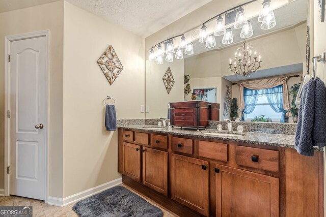 bathroom featuring tile patterned flooring, vanity, a textured ceiling, and an inviting chandelier