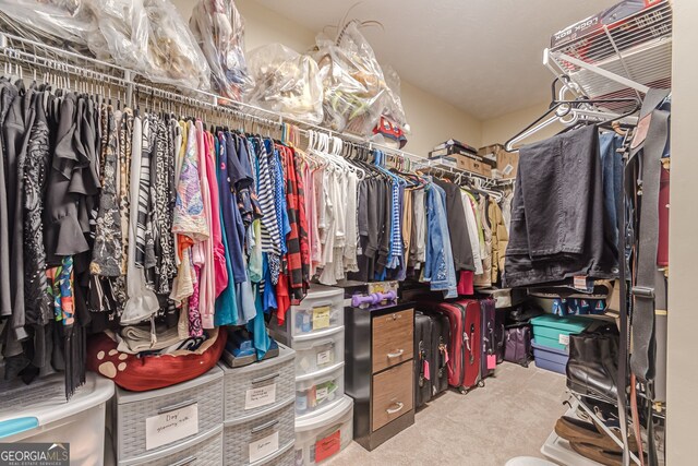 walk in closet featuring light colored carpet