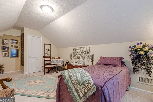 bedroom with light colored carpet, a textured ceiling, and vaulted ceiling