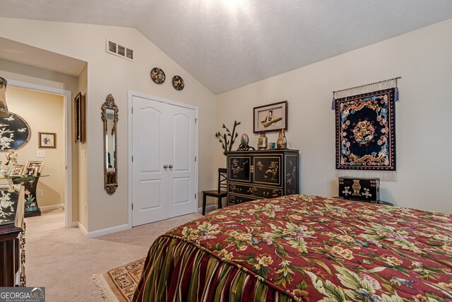 bedroom with a textured ceiling, light carpet, and vaulted ceiling