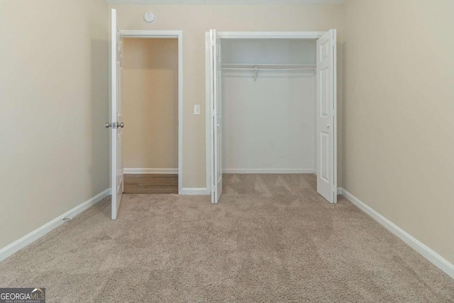 unfurnished bedroom with a closet and light colored carpet