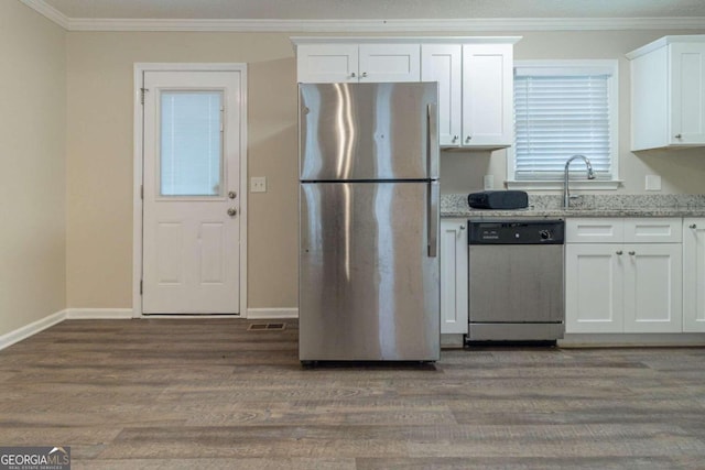 kitchen with stainless steel appliances, dark hardwood / wood-style flooring, light stone counters, white cabinets, and ornamental molding