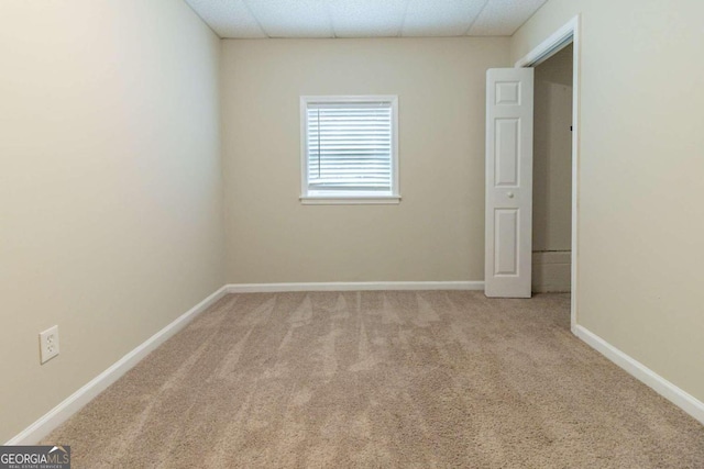 carpeted empty room featuring a paneled ceiling