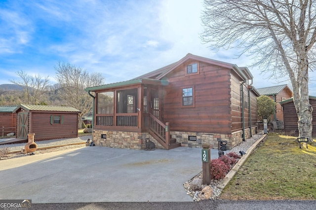 view of front of home featuring a shed, a front lawn, and a sunroom