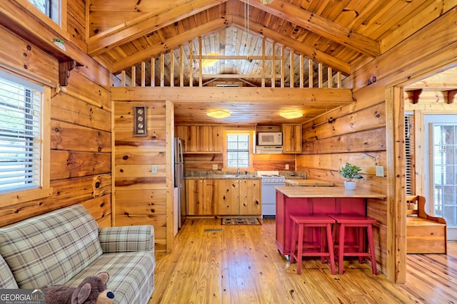 kitchen with high vaulted ceiling, wood walls, wood ceiling, white appliances, and light hardwood / wood-style flooring