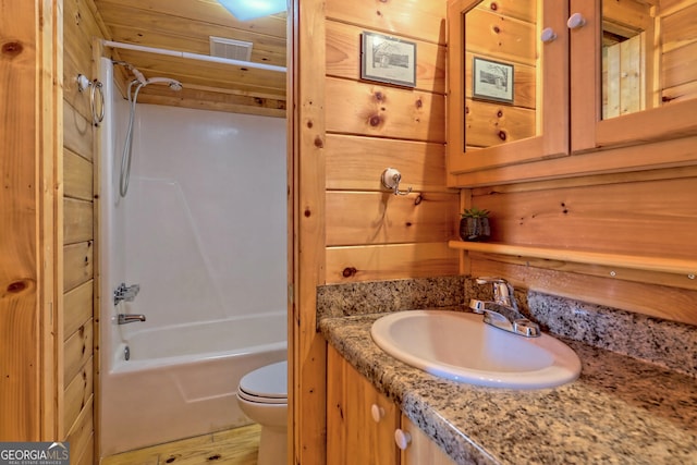 full bathroom with shower / bathtub combination, vanity, wooden walls, hardwood / wood-style flooring, and toilet