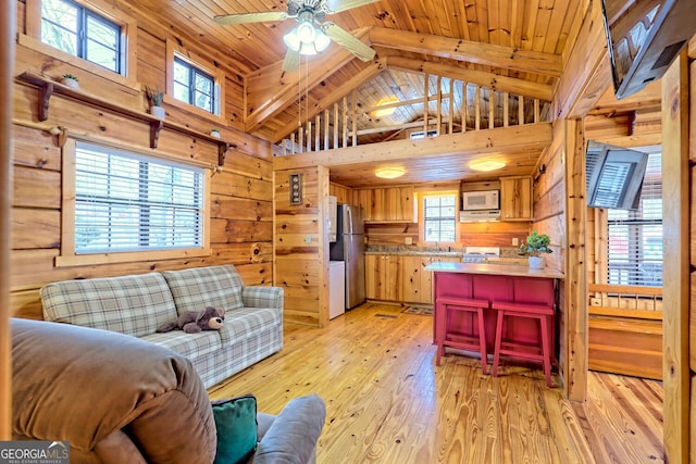 living room featuring wood walls, wood ceiling, vaulted ceiling with beams, and light hardwood / wood-style flooring