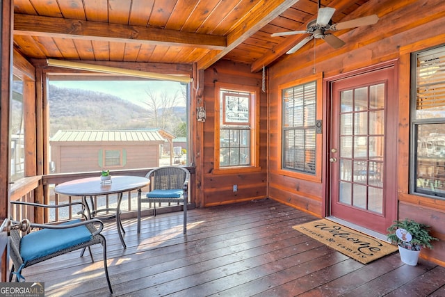 sunroom / solarium featuring ceiling fan, wood ceiling, and vaulted ceiling with beams