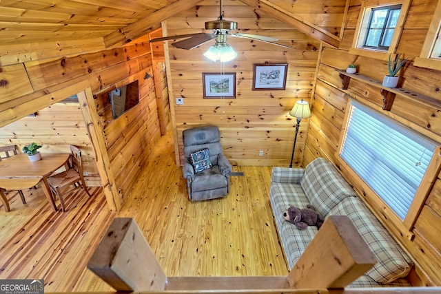 living area featuring hardwood / wood-style flooring, wooden walls, and lofted ceiling