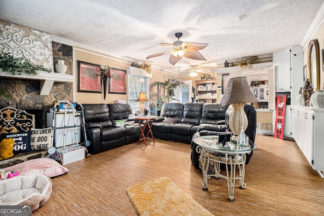 living room with ceiling fan, a textured ceiling, ornamental molding, and light wood-type flooring