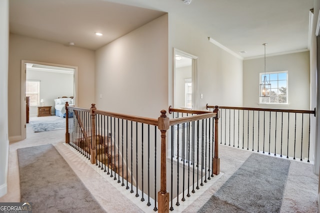 hallway with a chandelier, light carpet, and ornamental molding