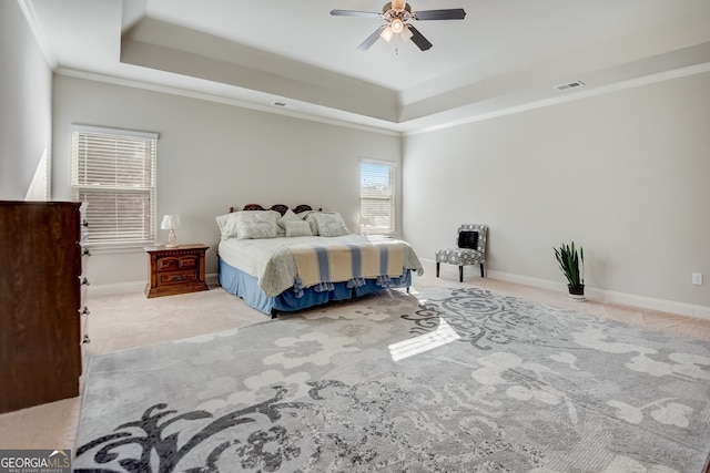 bedroom with ornamental molding, light colored carpet, ceiling fan, and a tray ceiling