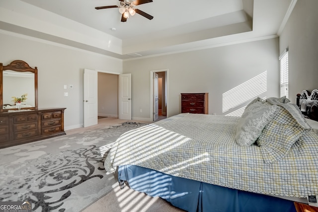 bedroom with ornamental molding, a tray ceiling, light colored carpet, and ceiling fan