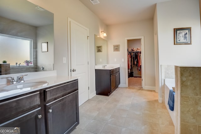 bathroom with a tub to relax in, vanity, and tile patterned floors