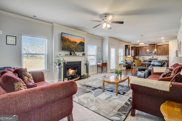 living room featuring light hardwood / wood-style floors, ceiling fan, and crown molding