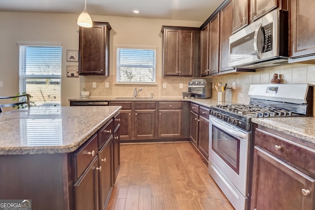 kitchen featuring light hardwood / wood-style flooring, a healthy amount of sunlight, decorative light fixtures, and gas stove