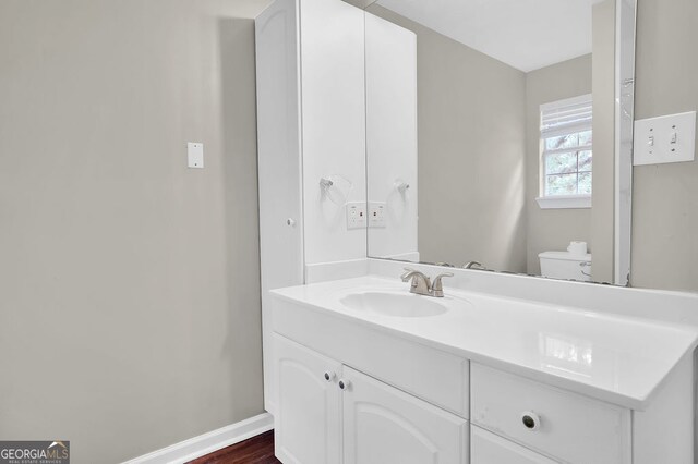 bathroom with toilet, vanity, and hardwood / wood-style floors