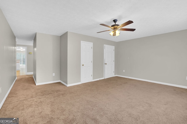 unfurnished bedroom with ceiling fan, a textured ceiling, multiple closets, and light colored carpet