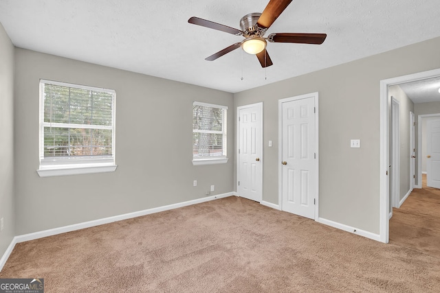 unfurnished bedroom featuring carpet flooring, a textured ceiling, and ceiling fan