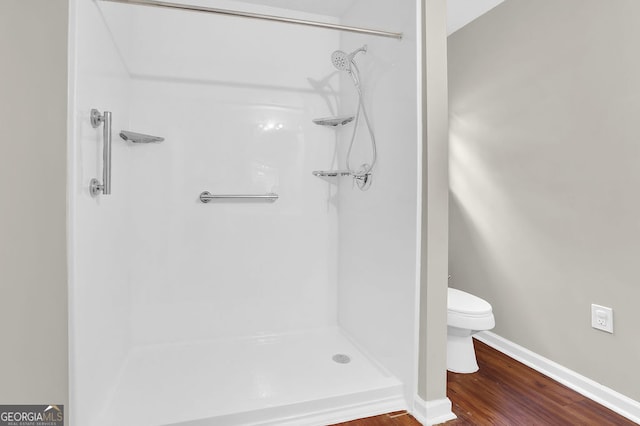 bathroom with wood-type flooring, toilet, and a shower