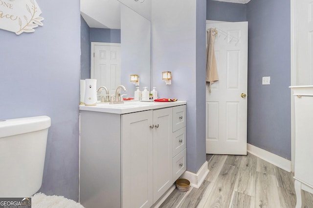 bathroom featuring toilet, wood finished floors, vanity, and baseboards