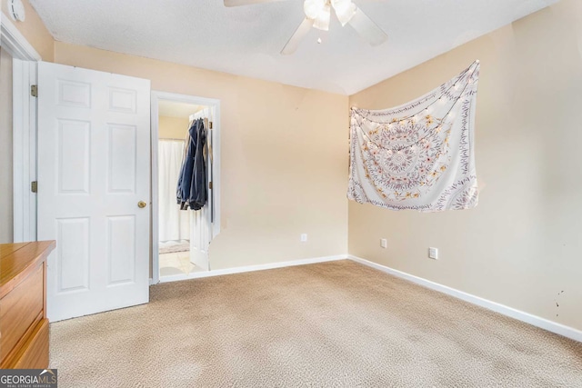 unfurnished bedroom with a ceiling fan, baseboards, carpet floors, a closet, and a walk in closet