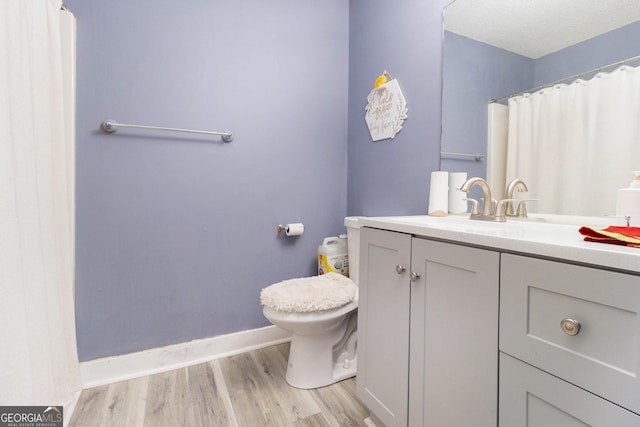 bathroom with toilet, curtained shower, wood finished floors, baseboards, and vanity